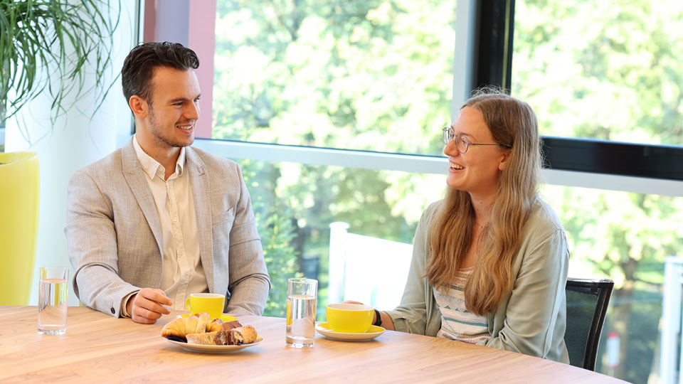 Alex und Katharina in Gesprächssituation mit Kaffee und Kuchen