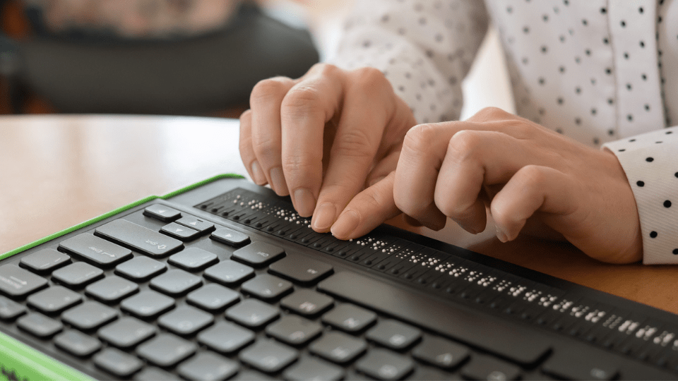 A blind woman operates a braille display with her hands to read a accessible digital document