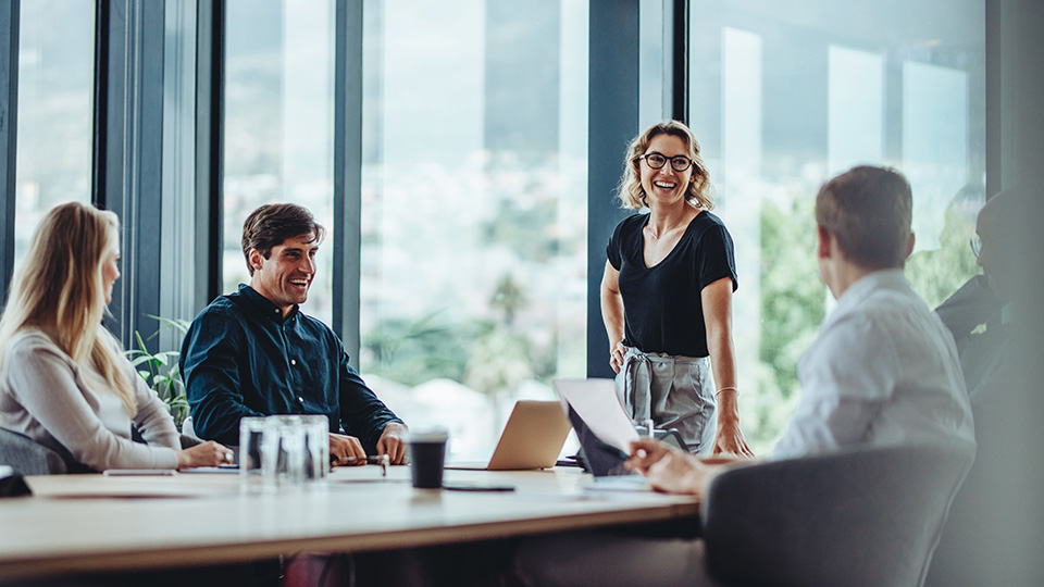 Four people sit together at a conference table and discuss with each other.