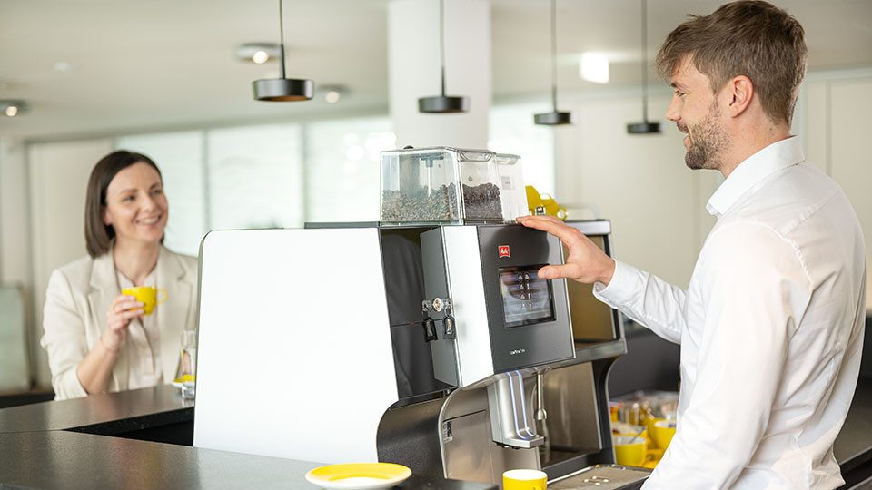 Zwei Personen unterhalten sich bei der Kaffeemaschine