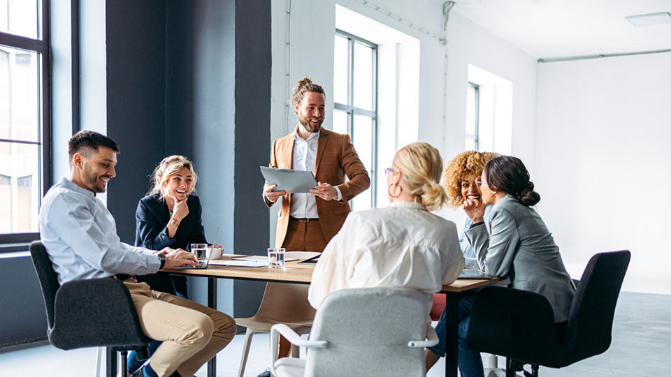 Six people in a conference room talking and working together.