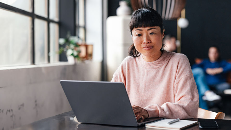 A female editor sits in front of a laptop and creates XML content.