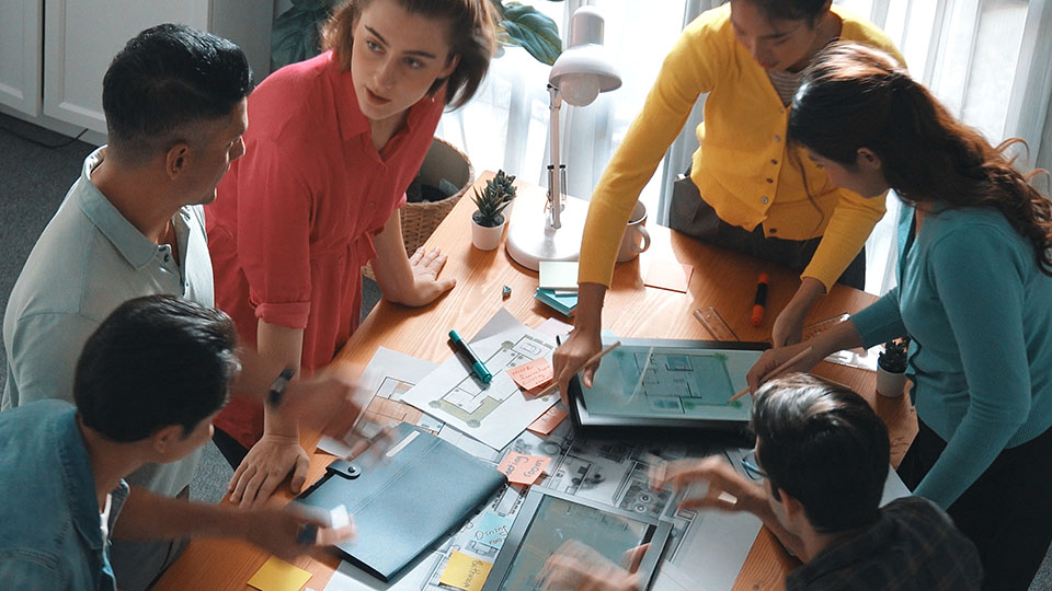 Young team standing at a table discussing.