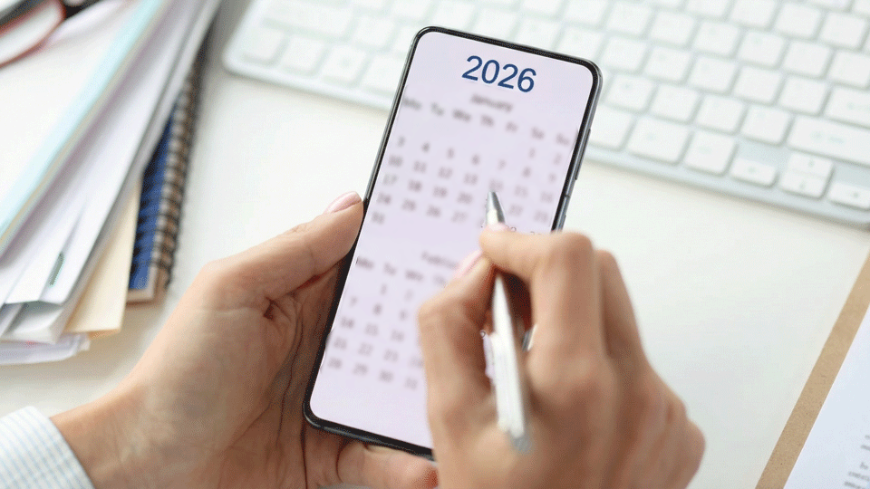 Person haelt Handy mit Kalender 2026 in der Hand